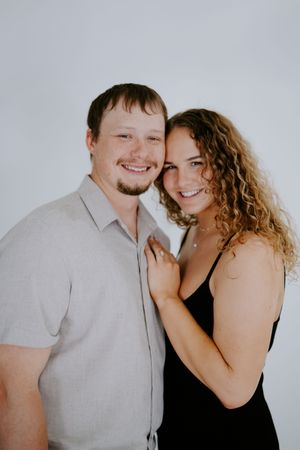 A couple poses together against a white background in contrasting black and gray outfits.
