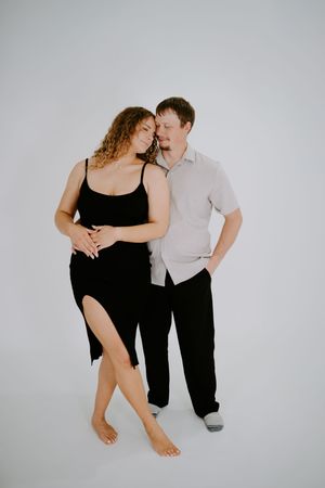 A couple shares an intimate dance pose against a minimalist white background.