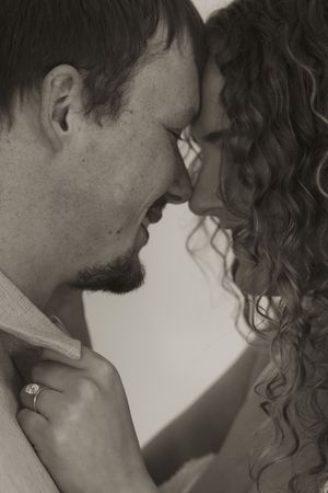 An artistic black and white portrait captures an intimate moment between a couple.
