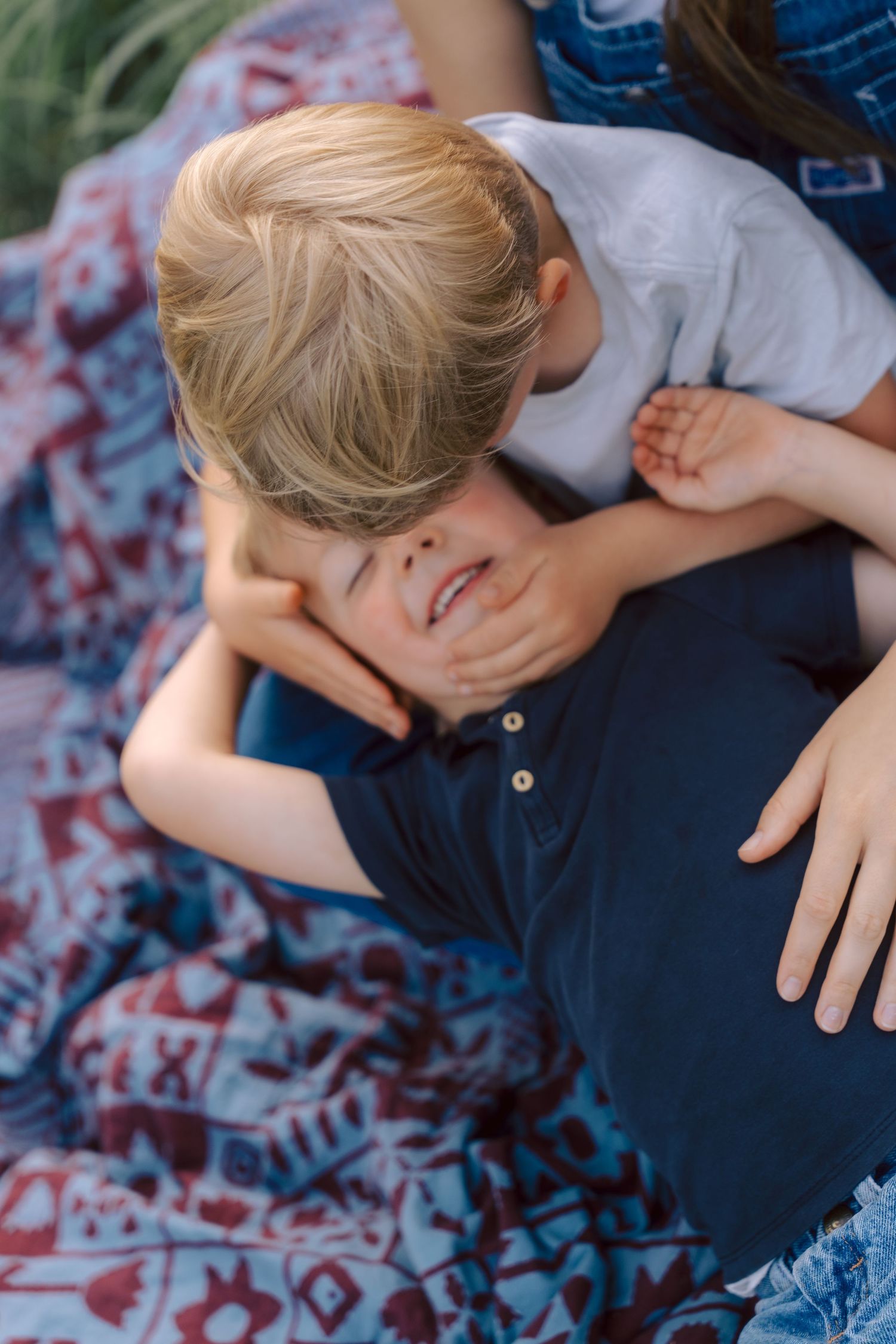 Sweet moment shared between two people laying on a geometric print blanket outdoors.