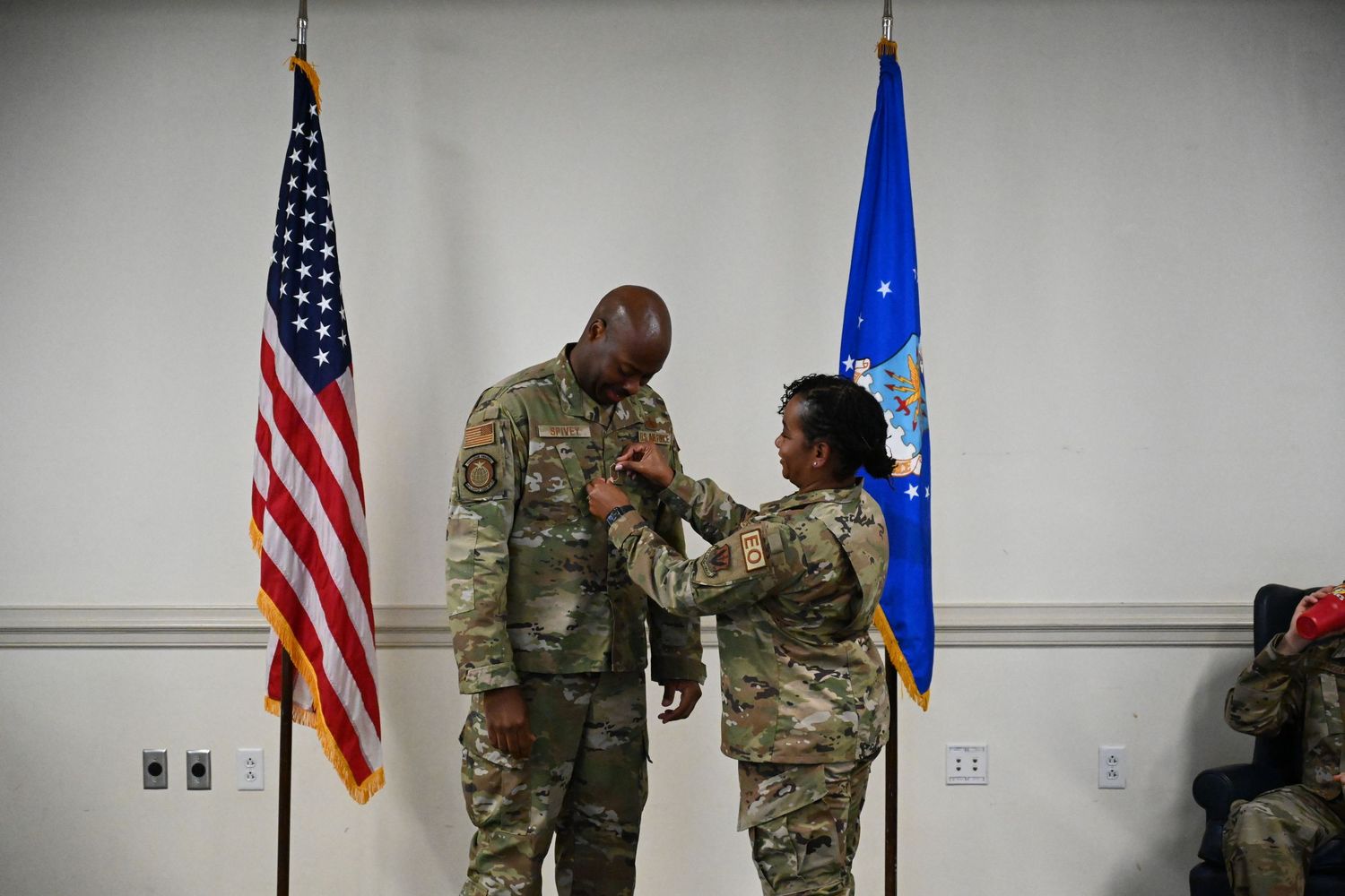 Military promotion or award ceremony with service members in front of American and Air Force flags.