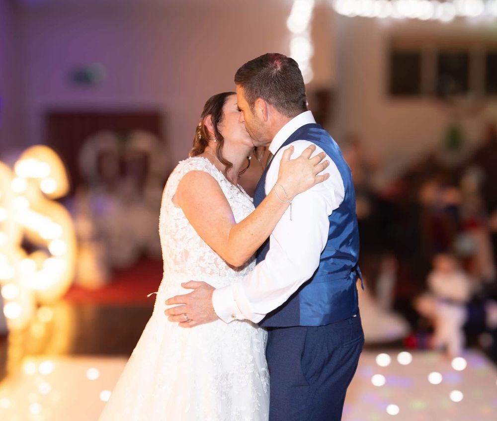 Newlyweds sharing their first dance under fairy lights at a wedding reception