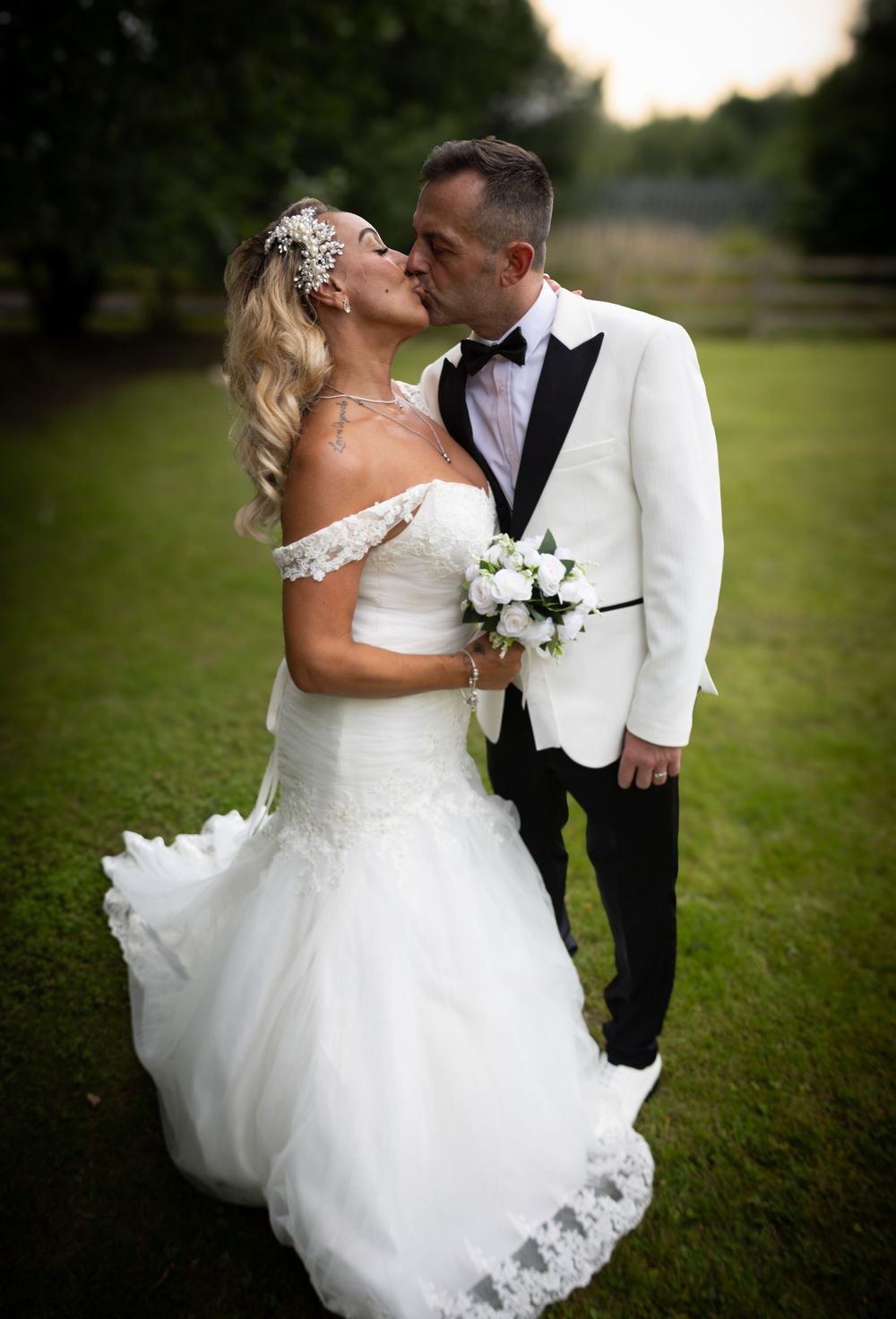 Romantic wedding couple shares intimate kisses and embraces in a series of outdoor sunset portraits on grassy field.