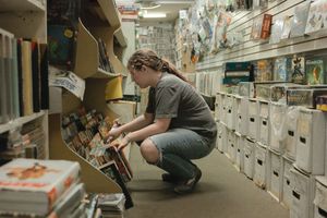 High school female student bends over to inspect comic books at Bizarro World in Davis, CA