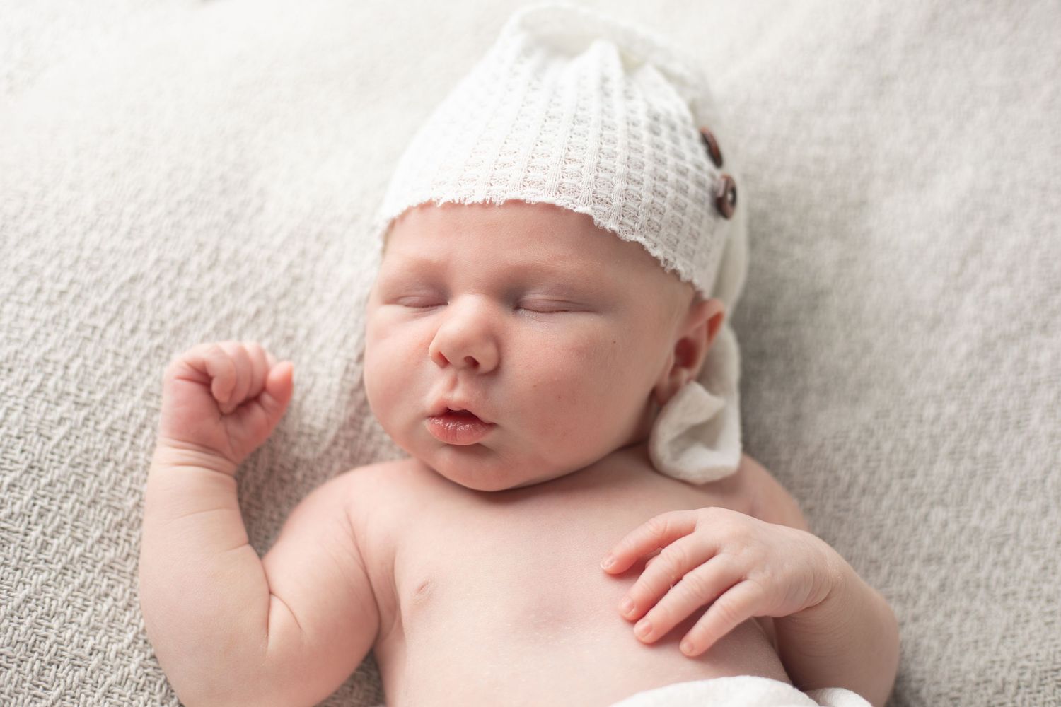 Newborn baby boy peacefully sleeping in neutral-toned wrap during Benfleet studio photography session