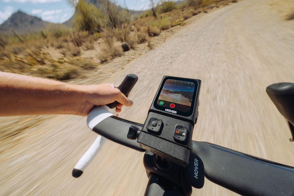 Point of view shot of cyclist looking at bike computer navigation display mounted on handlebars while riding dirt road.