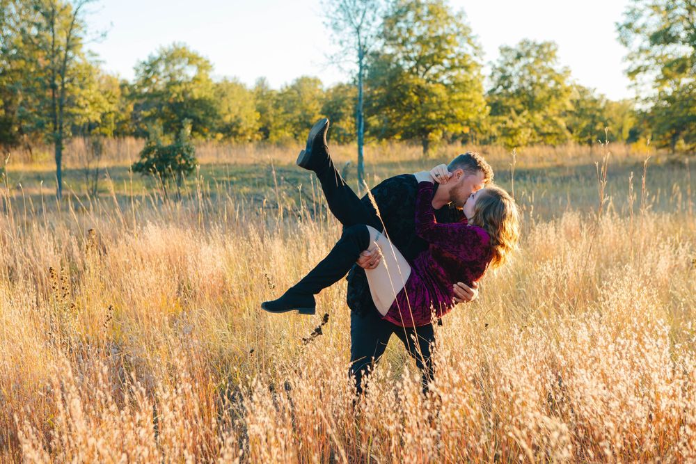 Playful couple enjoying a romantic moment in a golden autumn field.