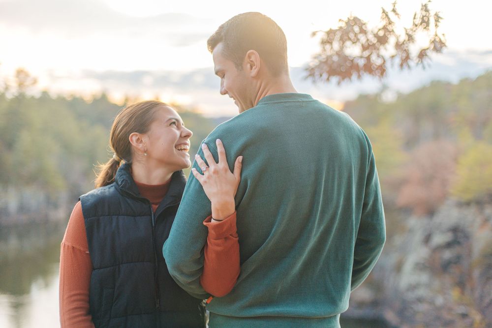Happy couple sharing a joyful moment outdoors with autumn scenery in the background.