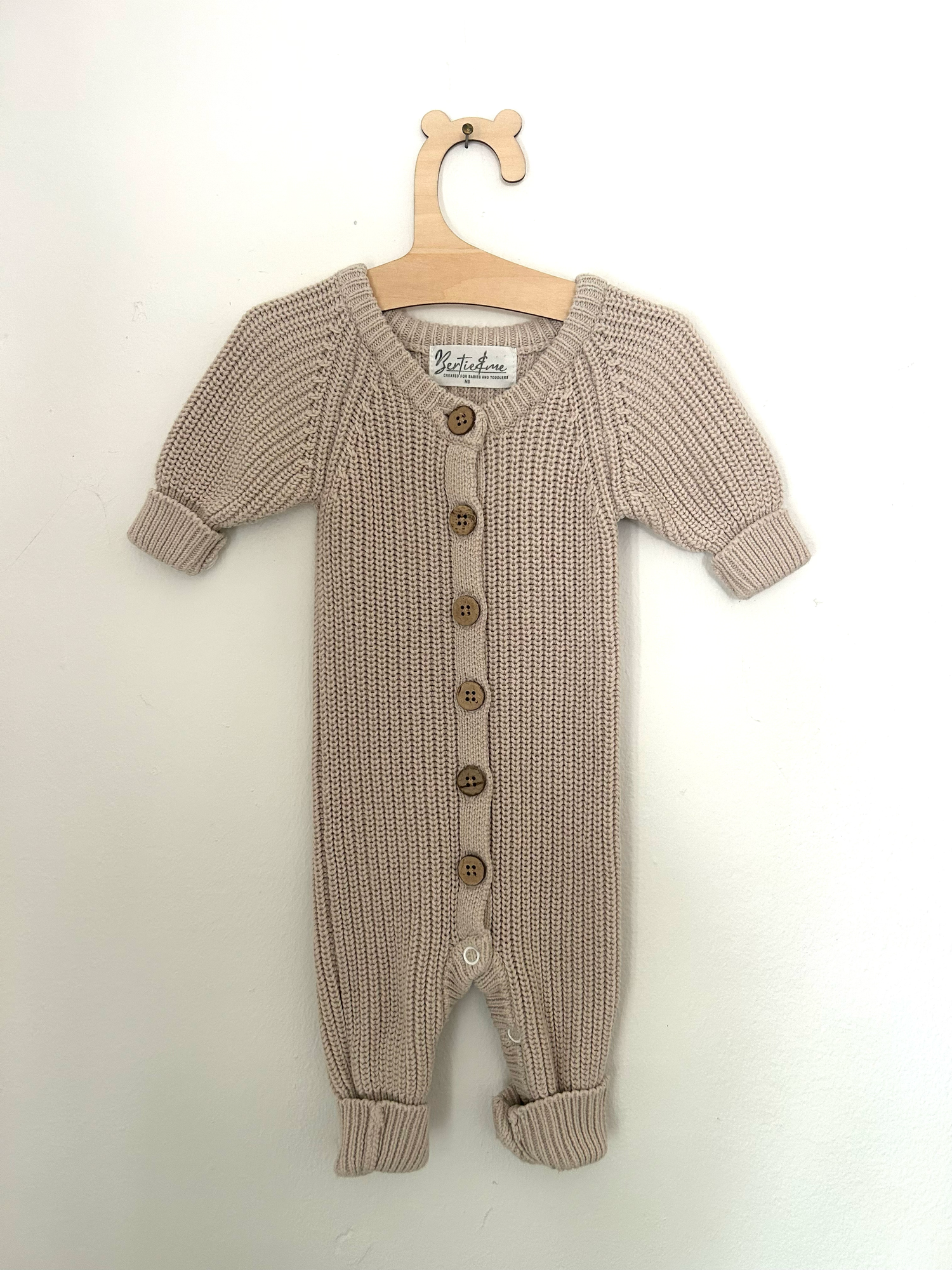 White baby romper with delicate pink embroidered floral design and ruffle details on straps.