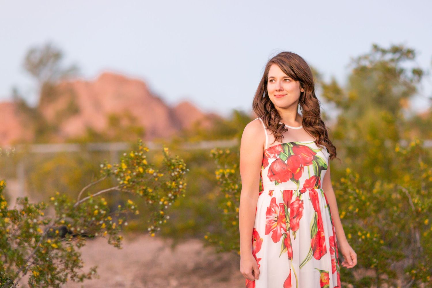 A floral dress complements the desert landscape with red rocks in the background.