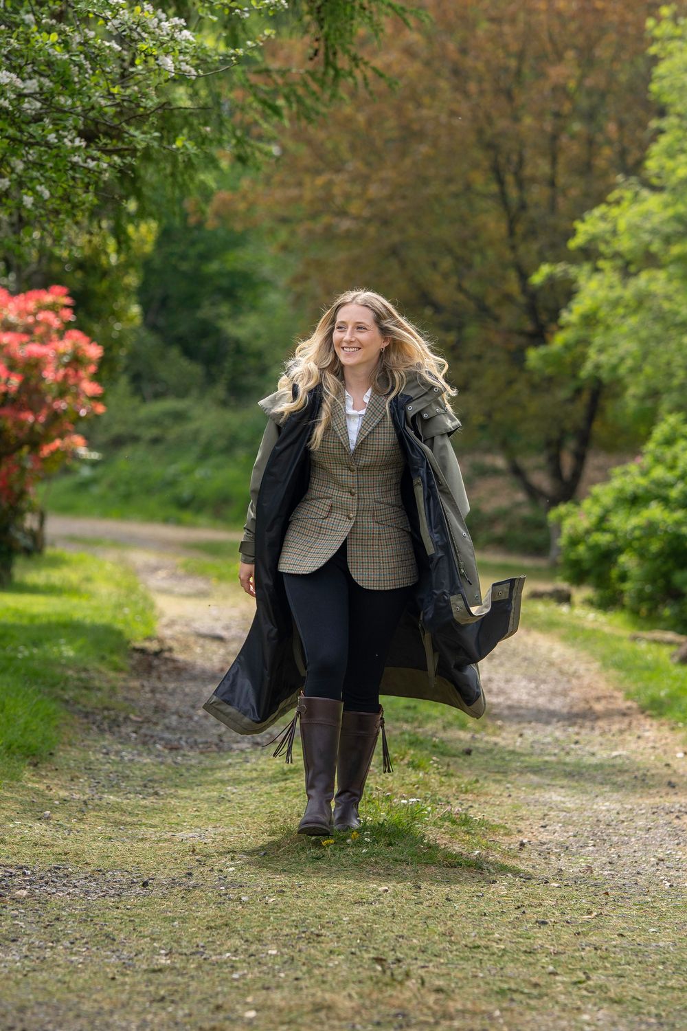 A sequence of images showing a figure in a tweed vest and dark coat walking and spinning on a dirt path in a lush park setting.
