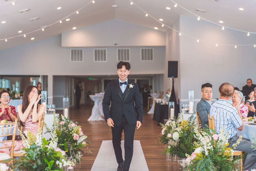Formal wedding setting with a decorated aisle runner and string lights in an elegant white interior.