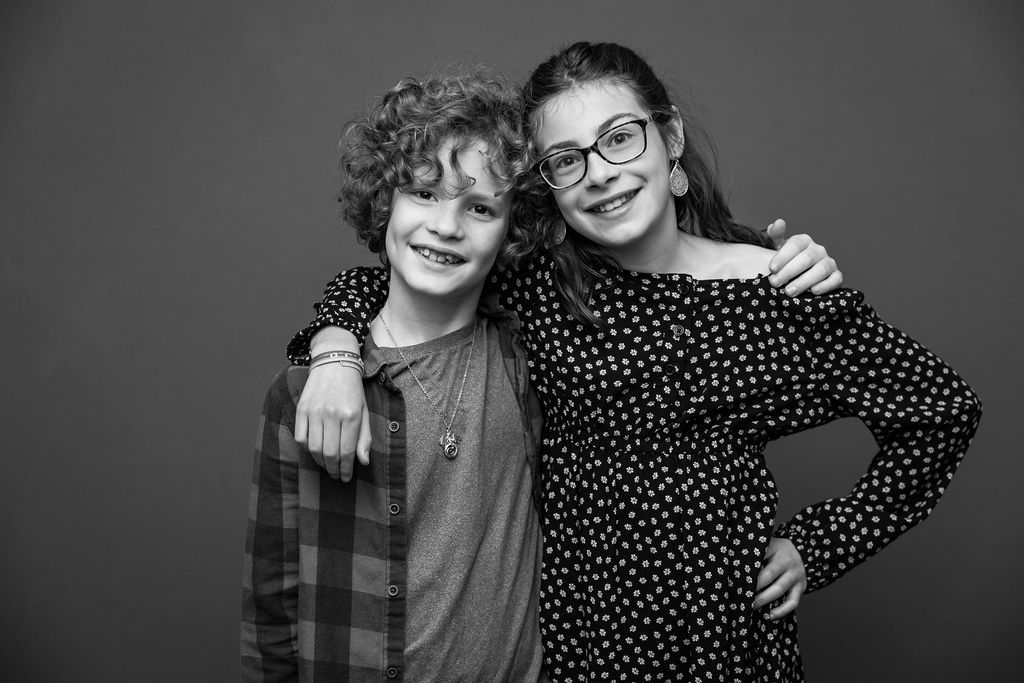 Black and white portrait of two young kids wearing casual clothes posing together against a plain background.