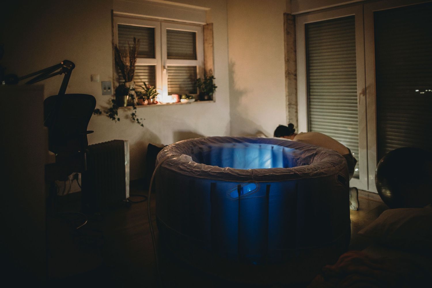 Parteira montando banheira com pouca luz na casa da gestante em parto domiciliar natural em Lisboa Portugal