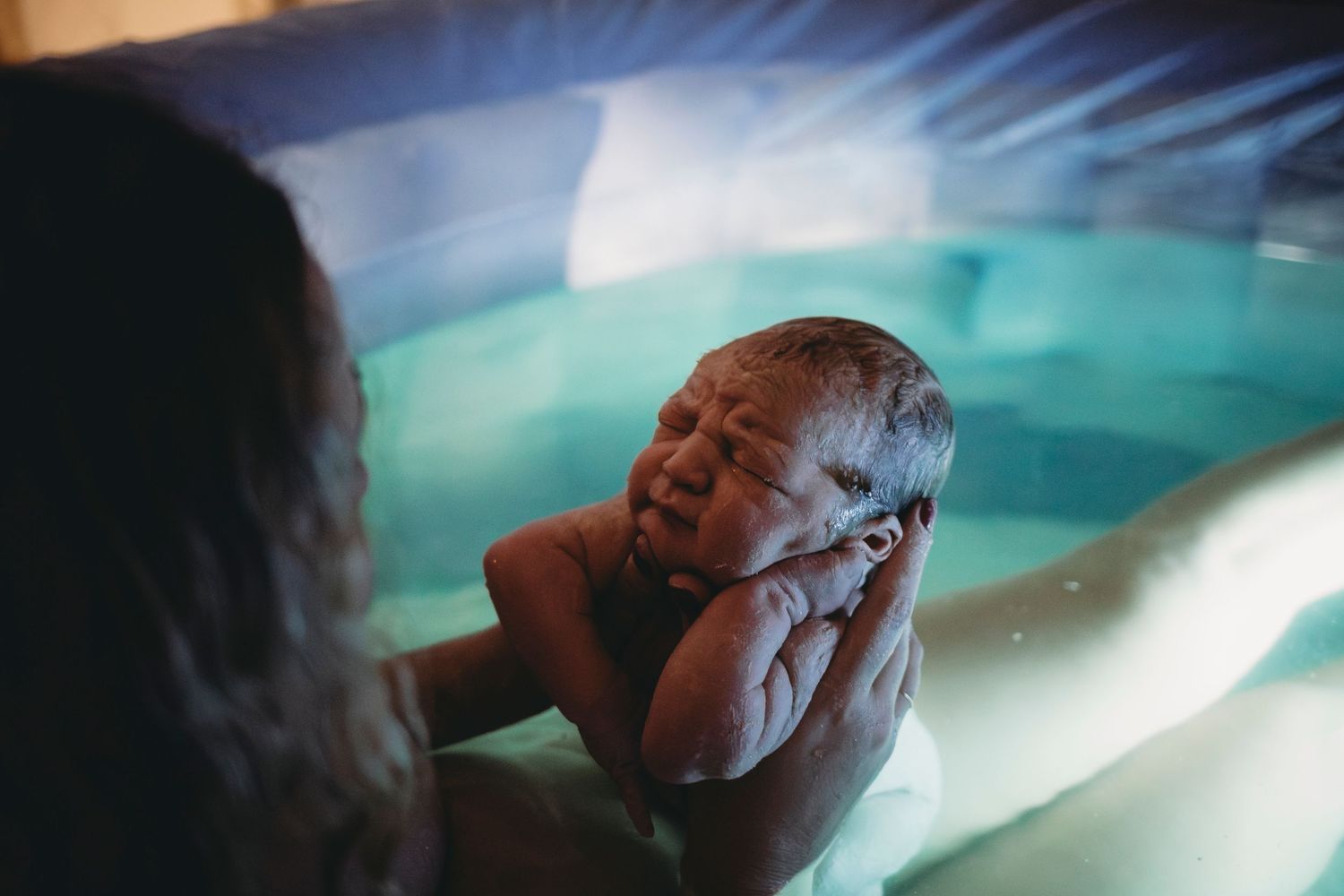 Bebé sendo segurado pela mãe na banheira após o parto domiciliar natural em Lisboa  Portugal