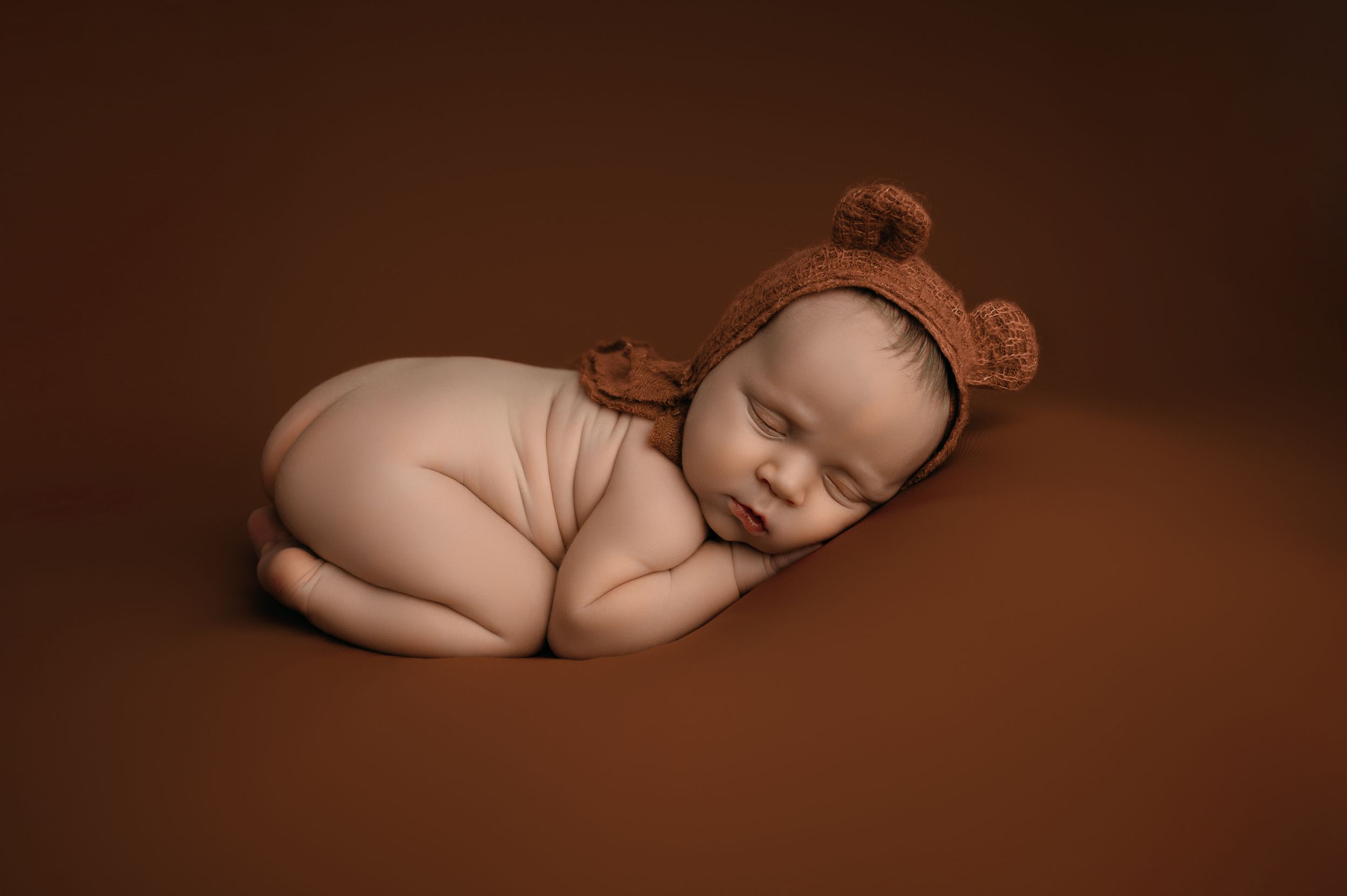 A black and brown photo series shows four sides of a sleeping newborn baby in a minimalist style.