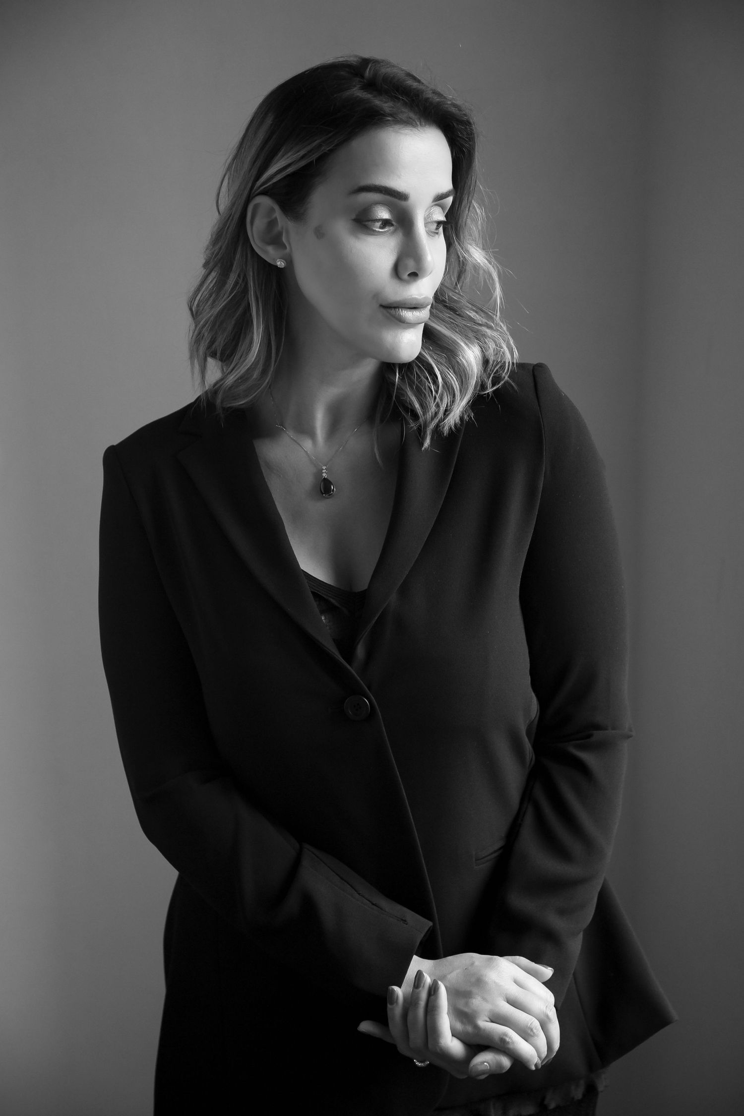 Black and white photo showing a person in white clothing standing against a light wall with palm leaf shadows.