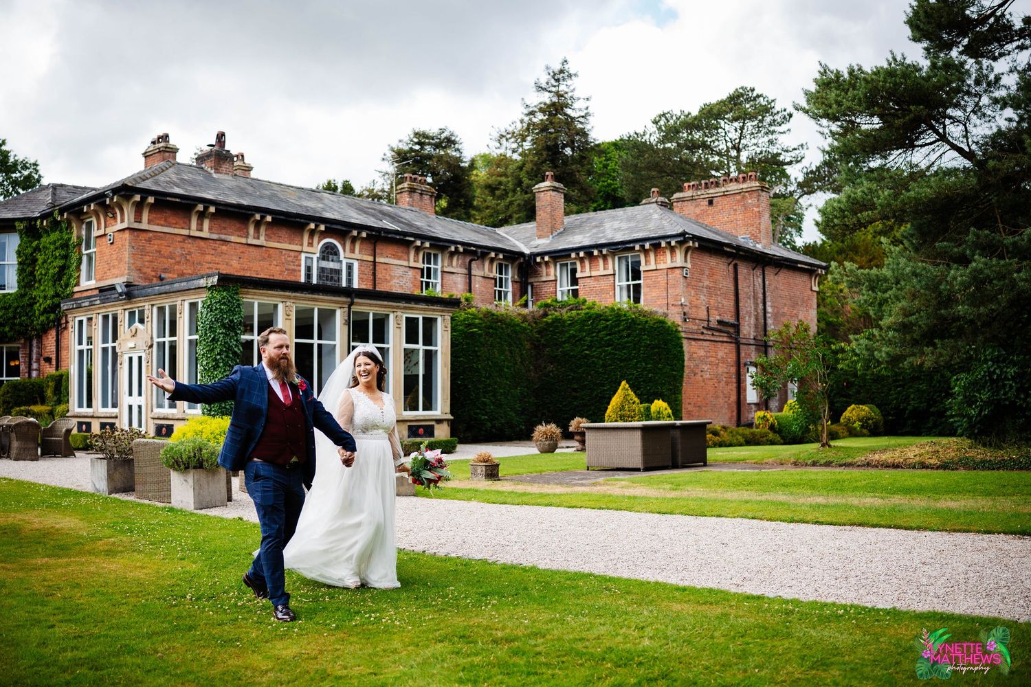 Bride & Groom joyfully celebrate on the lawn of a Bartle Hall Weddding Venue during outdoor countryside celebration captured by Lynette
