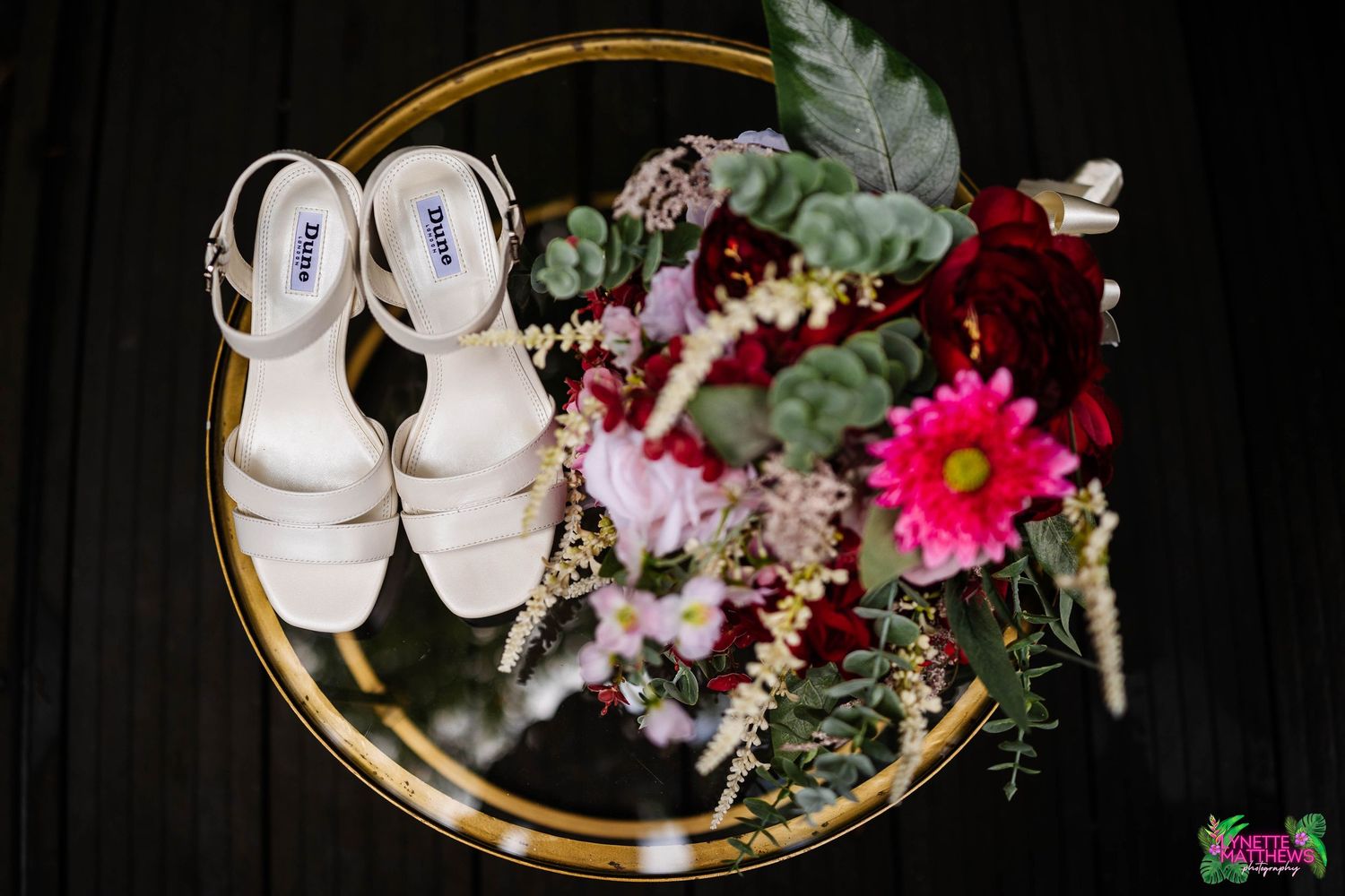 White bridal Dune Shoes placed beside a vibrant floral arrangement by foam flowers magull captured at Bartle Hall by Lynette Matthews