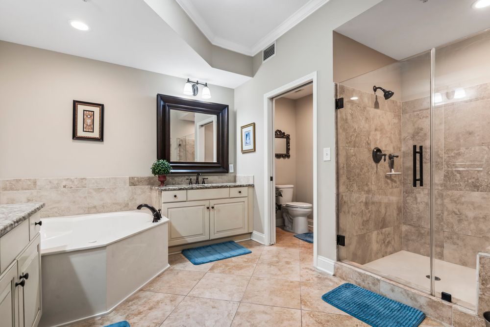 Spacious master bathroom with soaking tub, walk-in glass shower, and double vanity with tile floors.