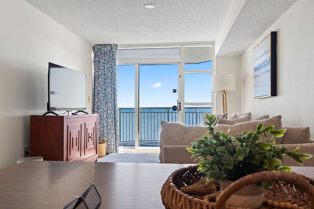 Bright oceanfront condo living room with floor-to-ceiling balcony doors offering stunning sea views.