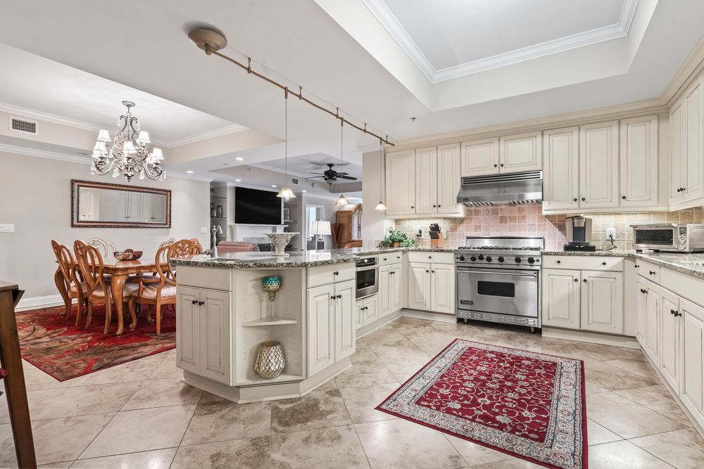 Large gourmet kitchen with white cabinets, center island, professional range, and adjoining dining area.