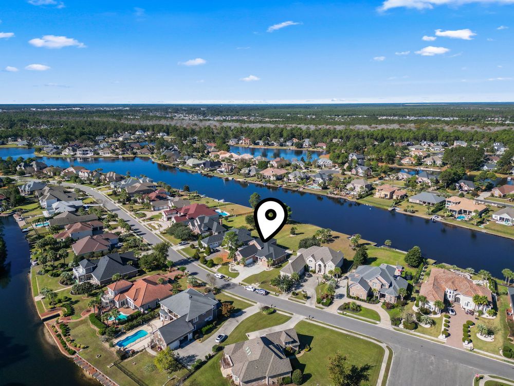 Aerial view of a waterfront neighborhood with homes along scenic canals surrounded by lush trees.