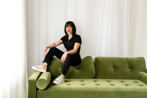 Myofunctional therapst Sarah Davis poses on a green couch at The Creative Photographer for her branding headshot