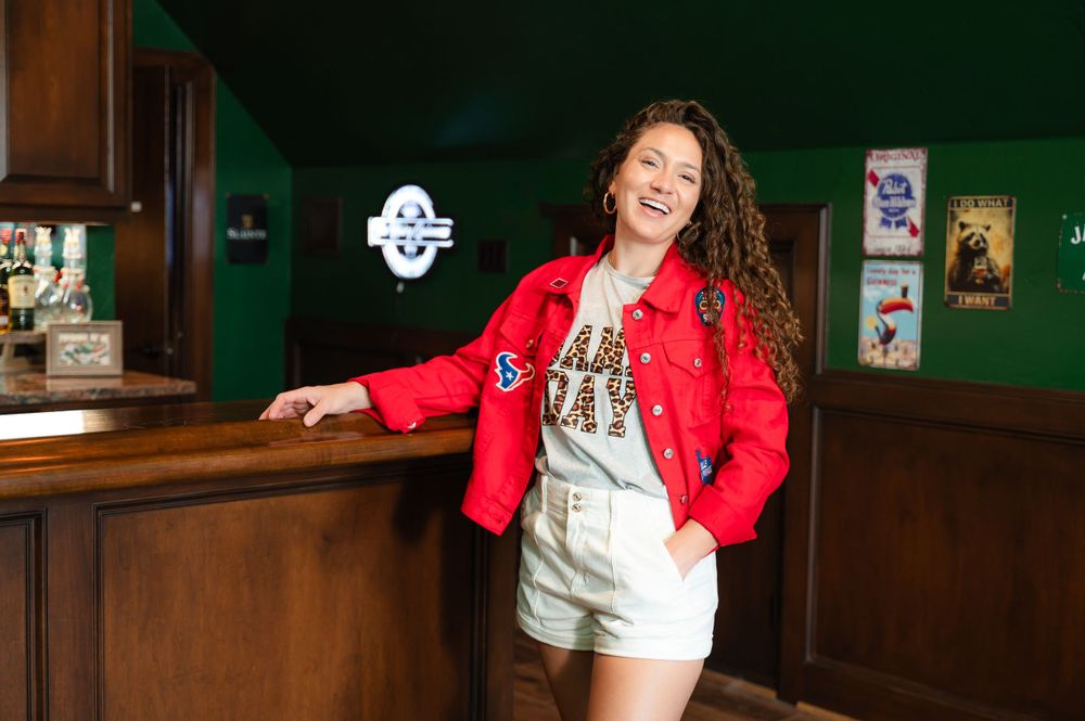 A casual portrait in a bar setting with dark green walls and wooden decor.