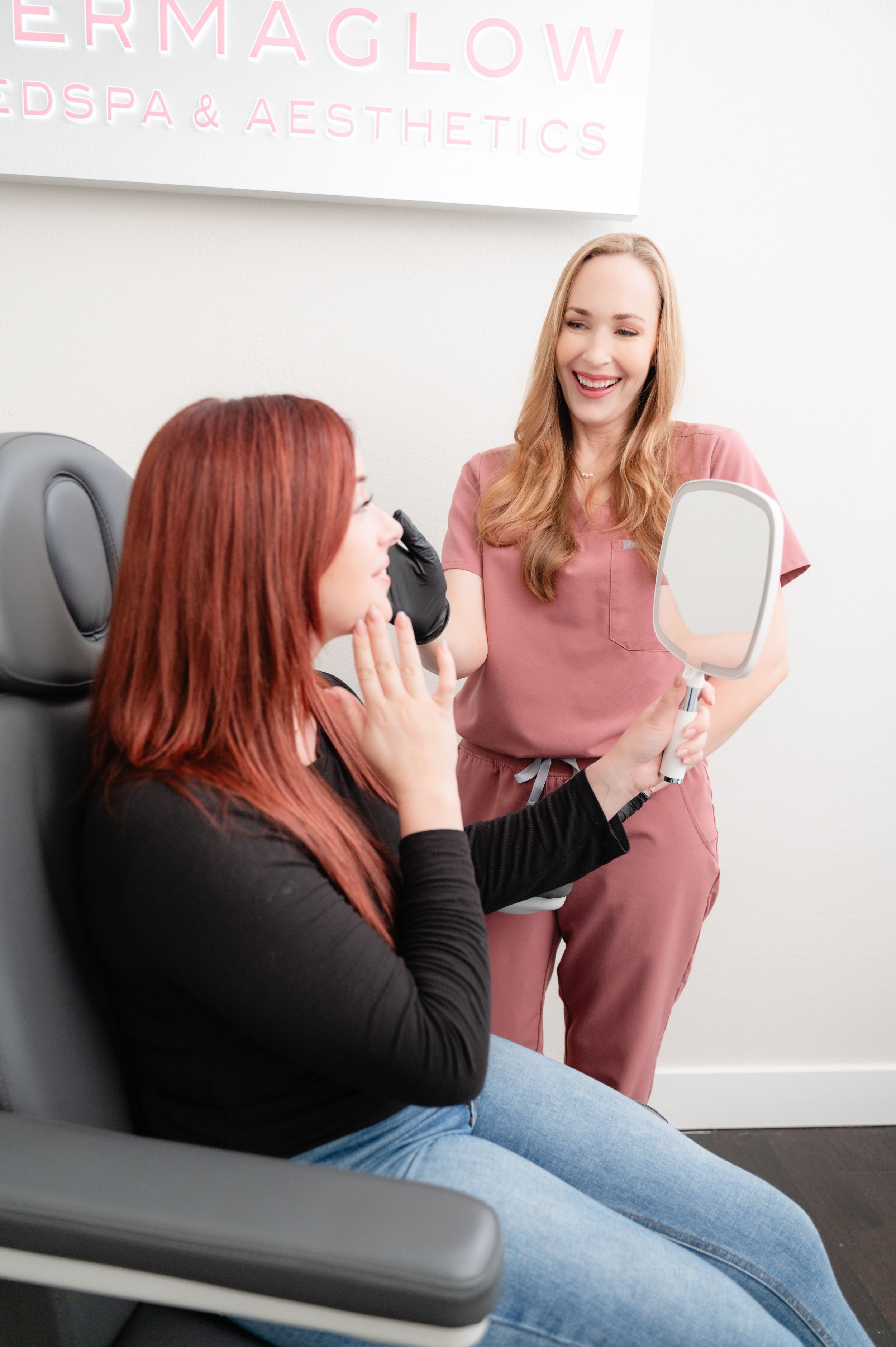 A medical aesthetics consultation session shows a staff member in pink scrubs discussing treatment with a client in a chair.