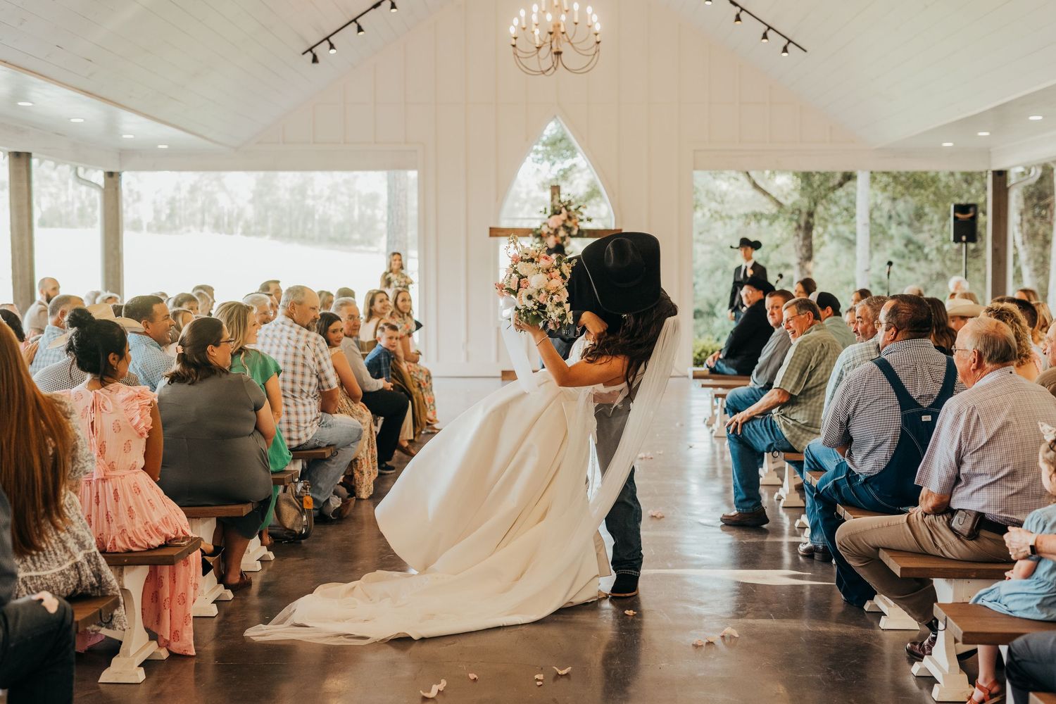A romantic moment shared between couple during their wedding ceremony in a bright wedding venue with guests watching in East Texas.