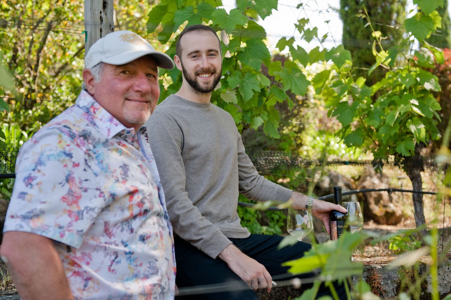 A father and son, dressed casually, enjoying a sunny day together in their vineyard in Soda Canyon in wine country. Napa Valley, CA.