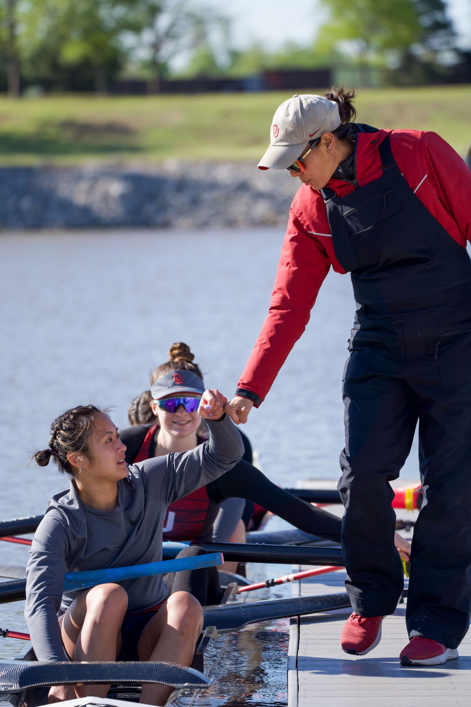 Coach leans over to instruct rowing athletes during training session on the water.