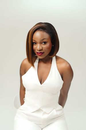 Studio portrait of someone in a glamorous white halter top posing against light background.