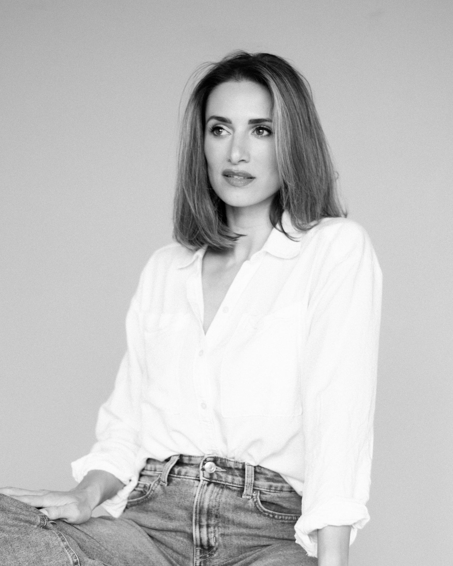 Black and white studio portrait photo series showcasing casually elegant styling with a white shirt and denim jeans.