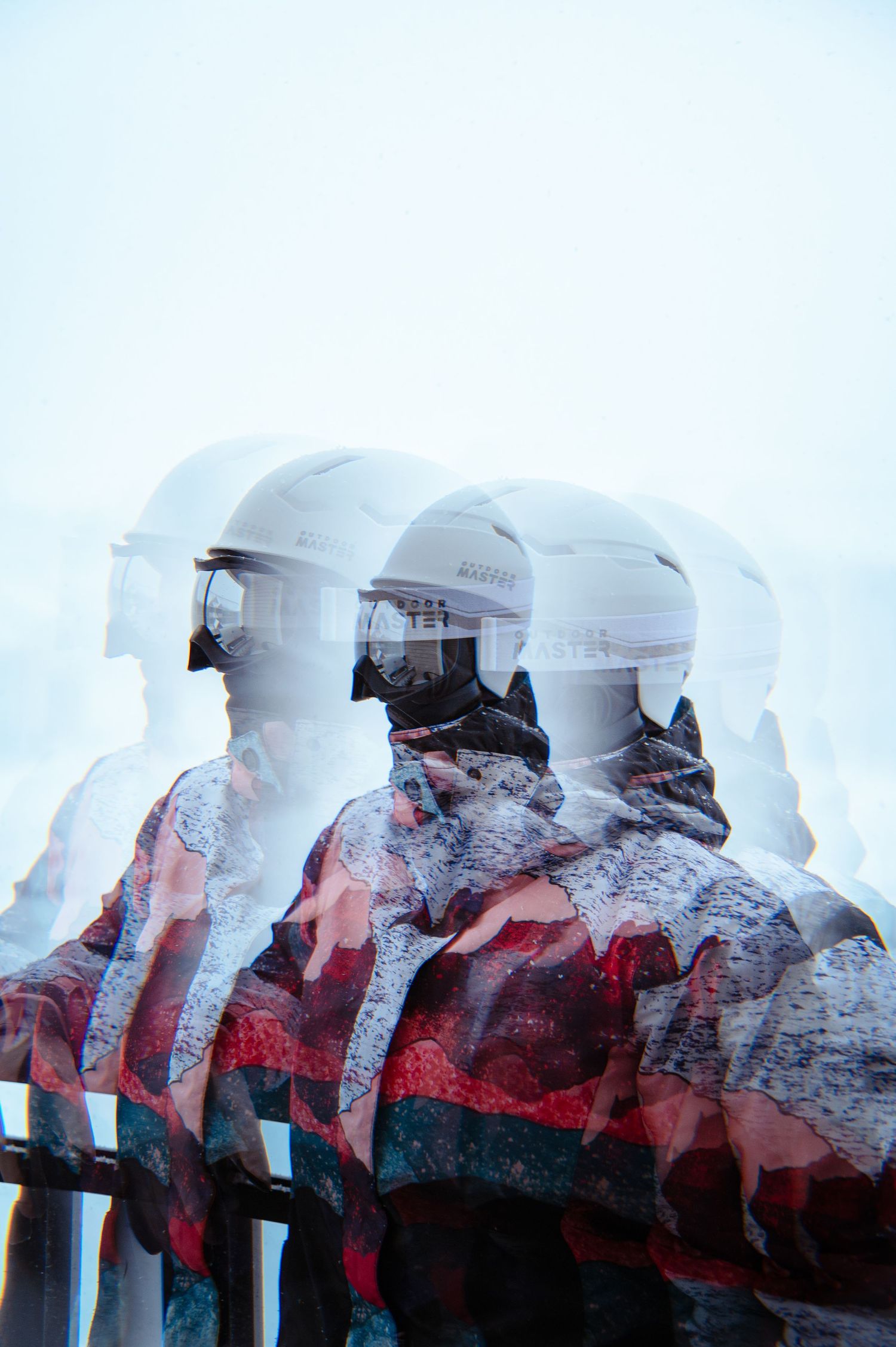 Multiple exposure portrait of three figures in white helmets against snowy mountain background.