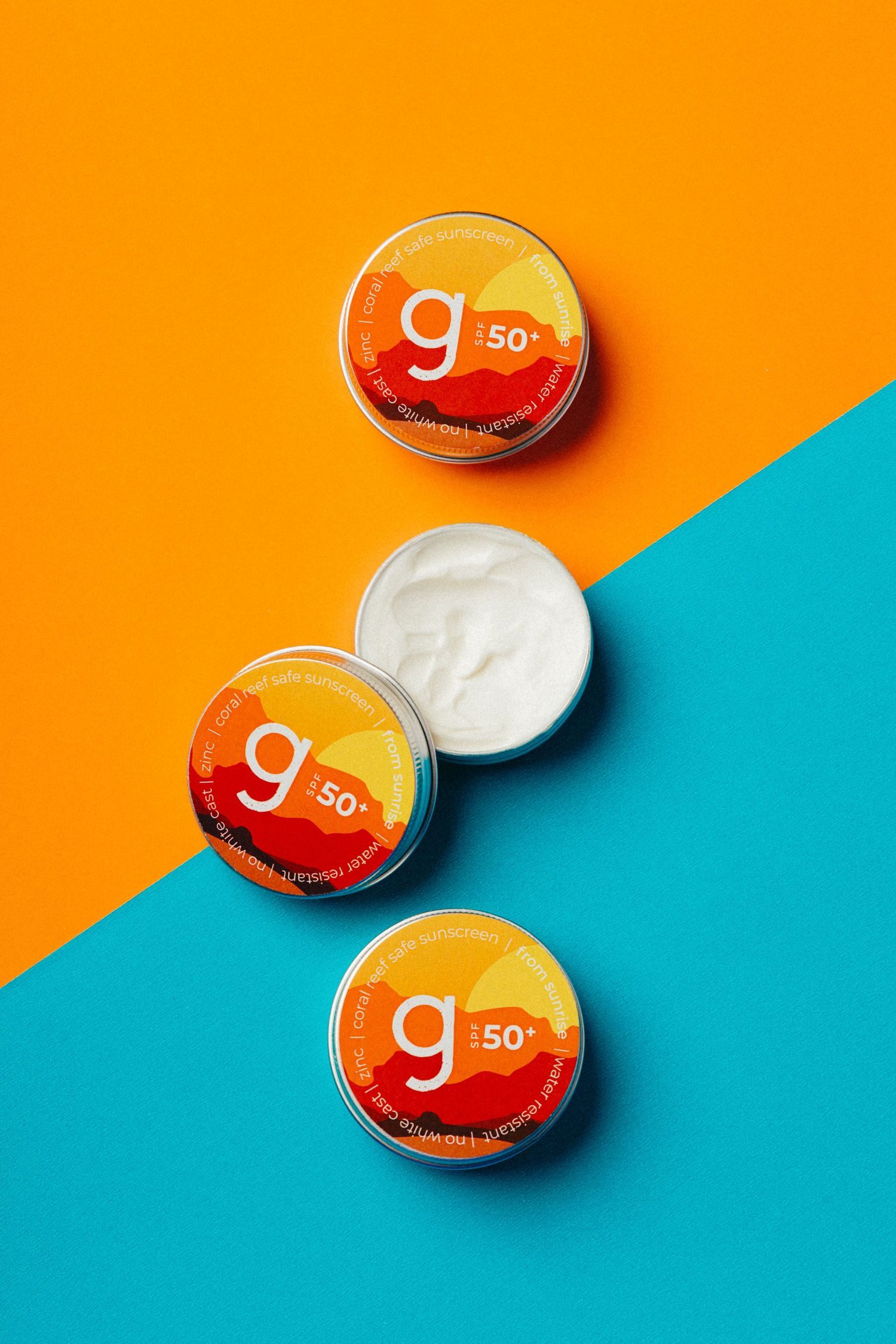 Three orange G50 moisturizer containers arranged on orange and turquoise background.