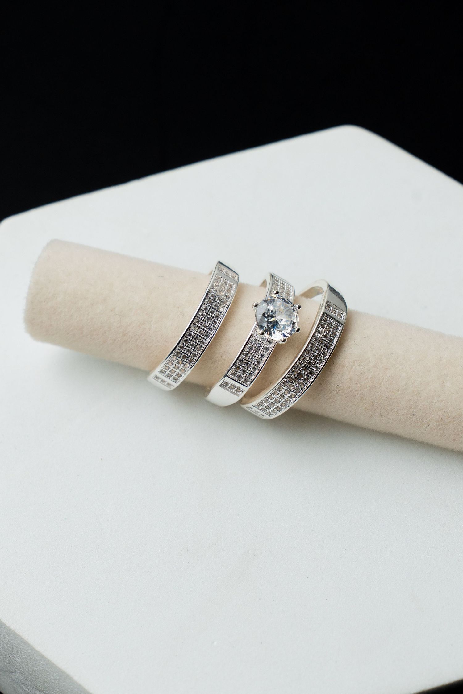 Elegant silver bridal ring set with diamond solitaire and pavé bands displayed on a jewelry roll.