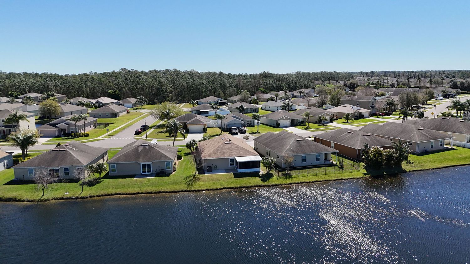 Aerial perspective of lakeside homes with manicured lawns and sparkling water views.