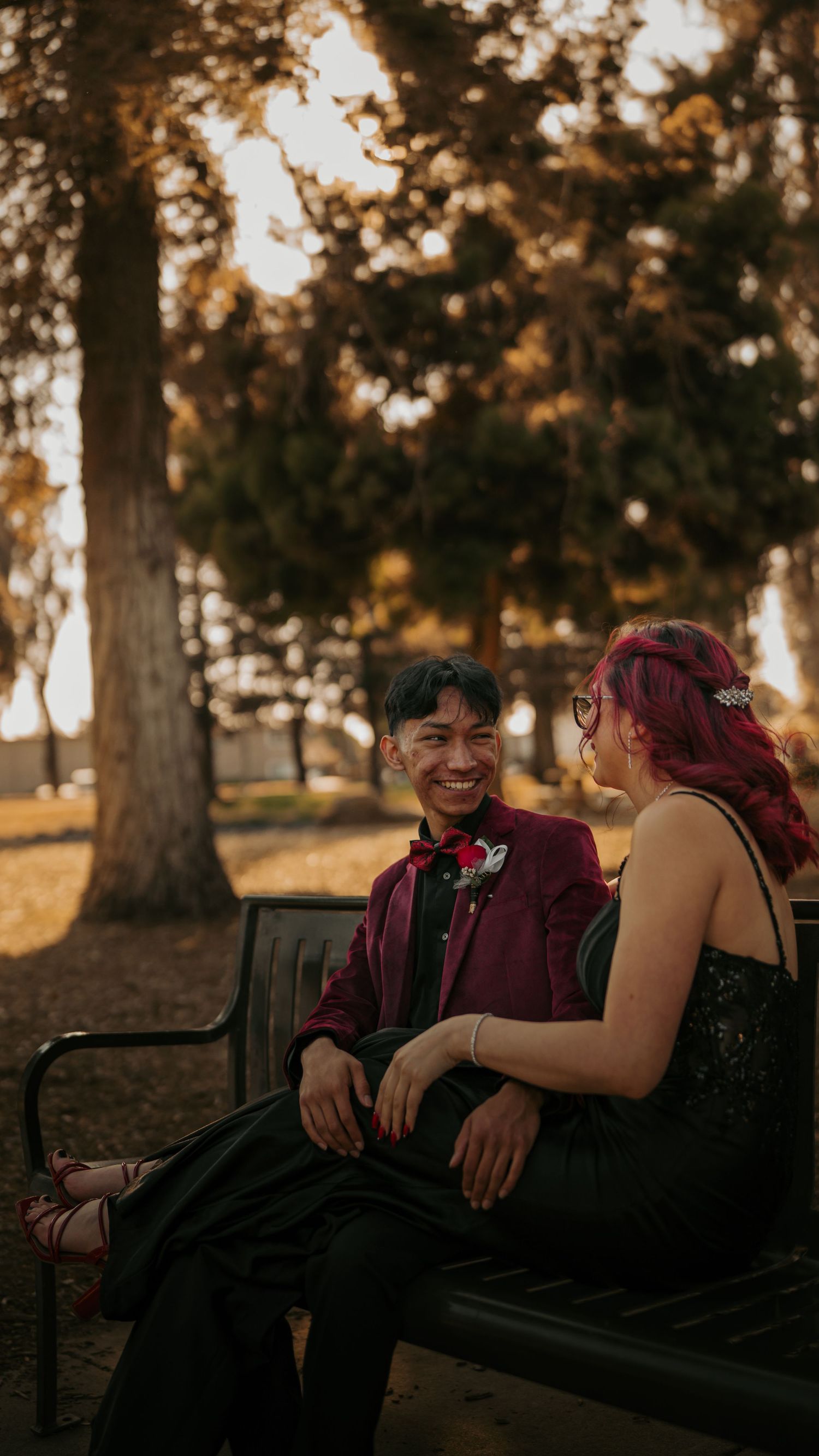 A couple shares a joyful moment at prom, with her in a sparkling blue dress and him in a black suit.