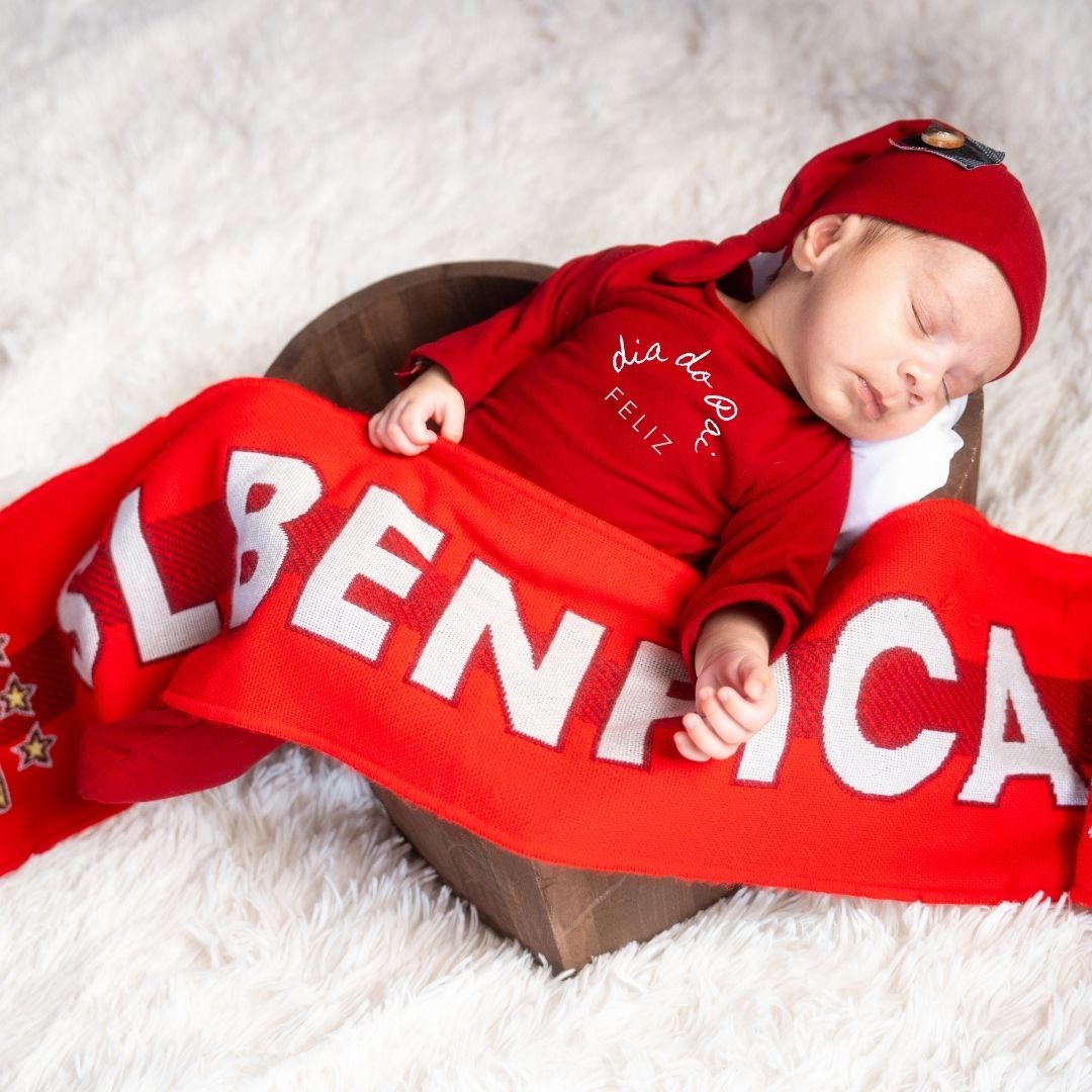 Baby sleeping on white surface with red America-themed blanket.