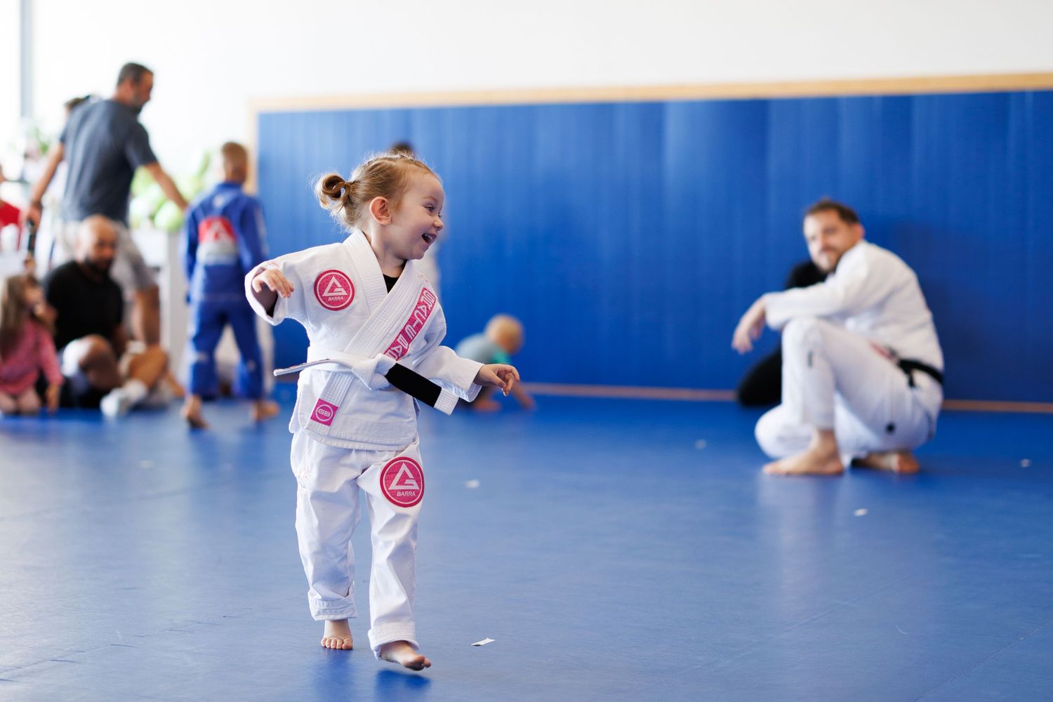 Students practicing Brazilian Jiu-Jitsu techniques on blue mats in a training facility.