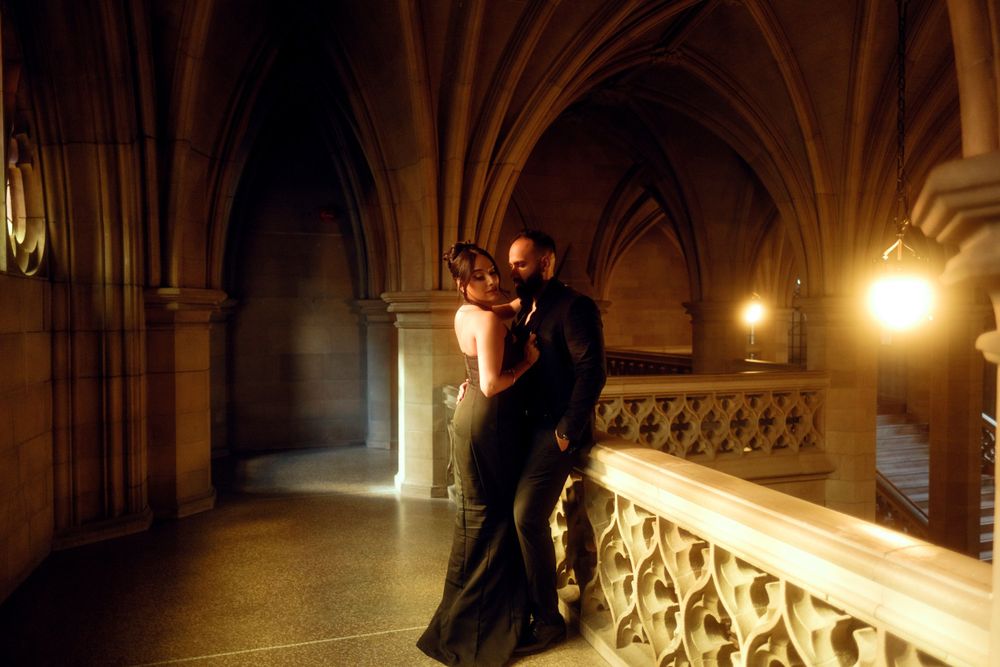 A romantic couple dancing in a dimly lit Gothic hallway with arched stone architecture and warm glowing lights.