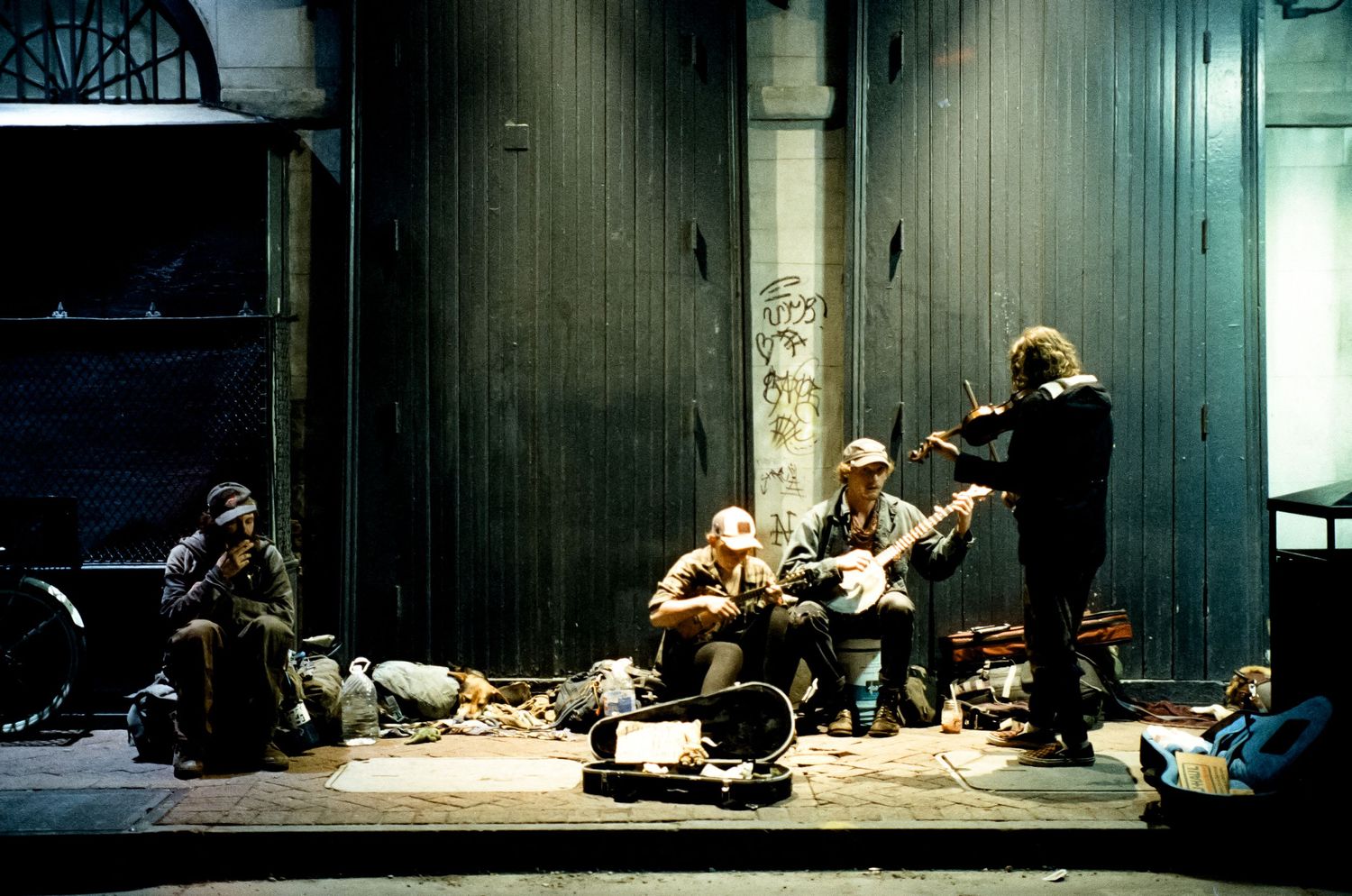A small group of people gather with musical instruments in a dimly lit industrial space.