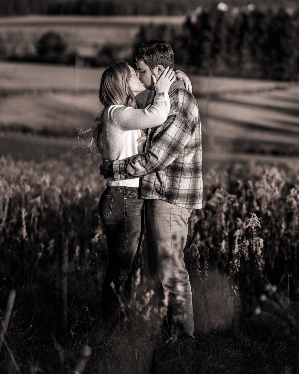 Black and white romantic portrait of couple embracing in a meadow.