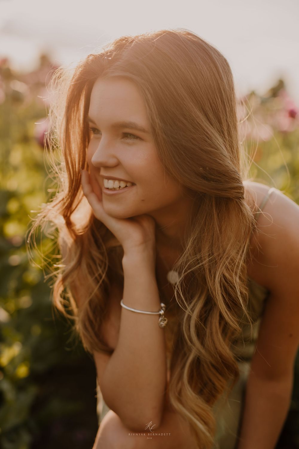 Portrait of a young woman in golden sunlight among greenery.