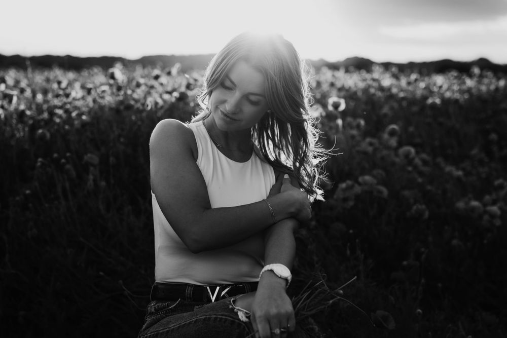 Black and white portrait of person in field with sunlit hair.