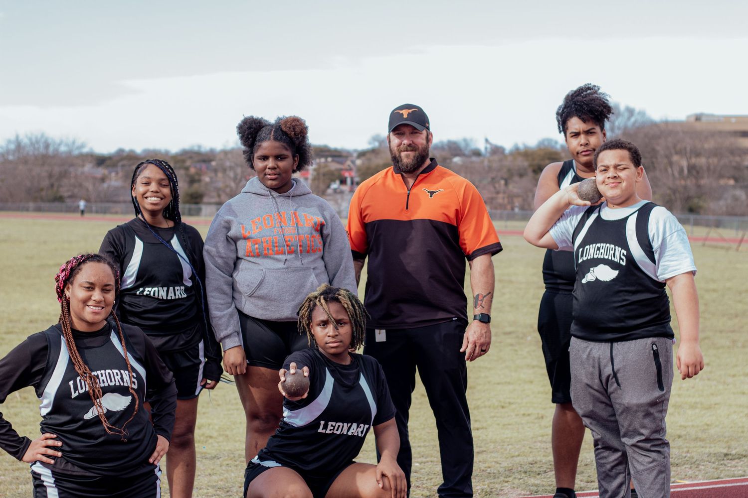 A group of athletes in athletic gear pose together on a field during an outdoor training session.