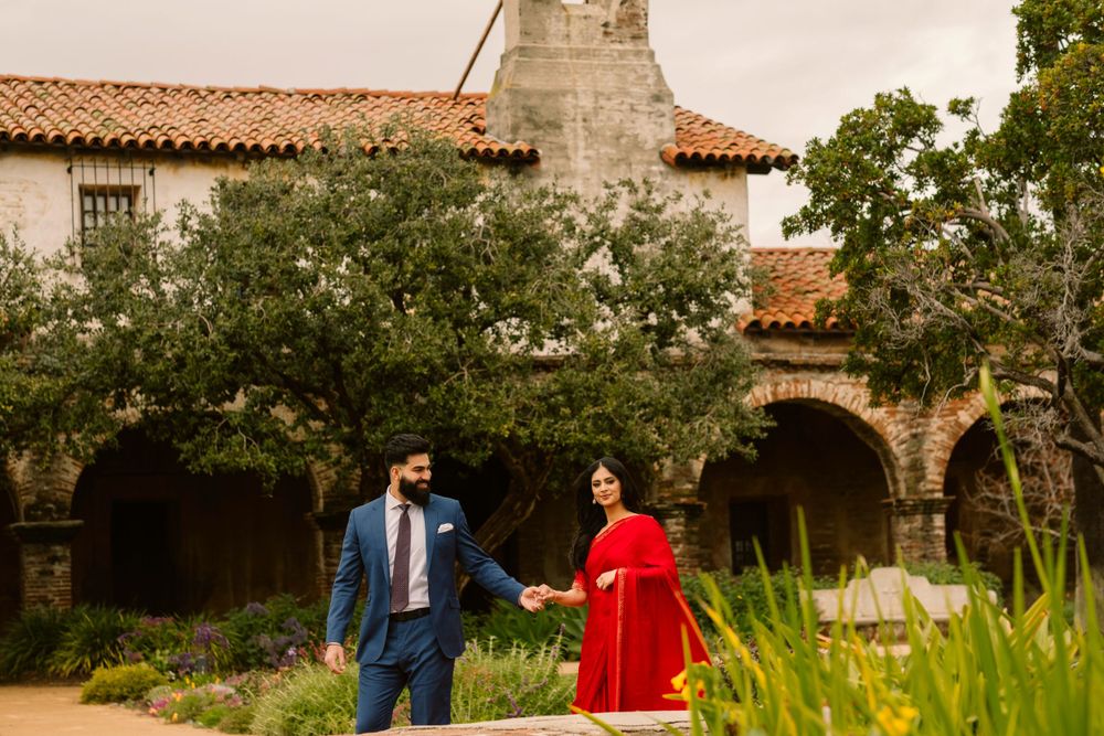 A couple walks through the courtyard of a Spanish colonial style building with terracotta roof and stone arches.