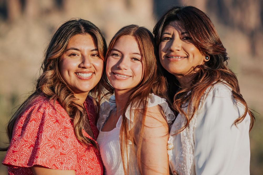 Friends pose together in warm sunlight against desert backdrop.